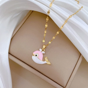 Macro detail of a golden whale necklace with pink enamel and sparkling zircon accents