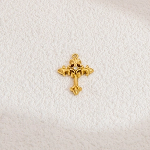 Macro detail of a golden vintage cross pendant with white zircon and baroque carvings