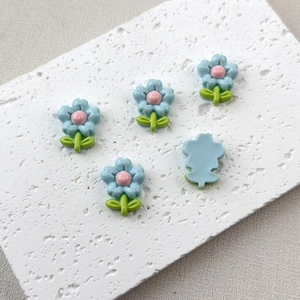 Macro shot of five blue resin flower charms for DIY hair clips on a white stone base
