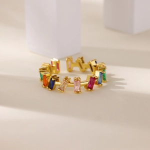 Detail view of gold open ring with colorful rectangular cubic zirconia on a stone base