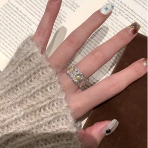 Close-up of a vintage two-tone daisy flower open ring worn on a finger with book background