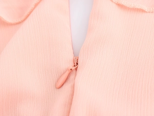 Detail of invisible zipper on light pink textured fabric for French style V-neck dress
