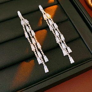 Macro shot of silver tassel earrings with sparkling crystals on black display