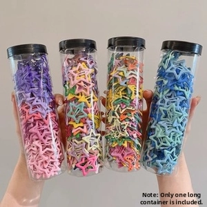Close-up of star-shaped colorful metal hair clips in transparent cylindrical packaging jars