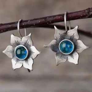 Gros plan de boucles d'oreilles vintage en argent avec gemme bleue sur une branche