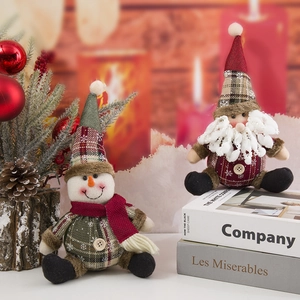 Gnomo y muñeco de nieve de peluche navideños con cuadros rojos junto a la chimenea