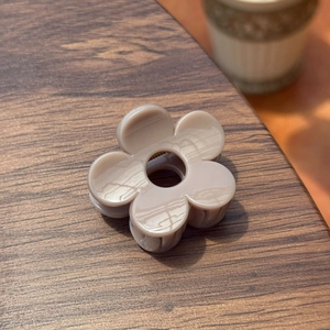 Vue détaillée d'une pince à cheveux fleur de 5cm beige sur une surface en bois