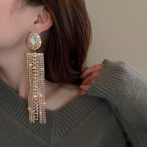 Close-up of long gold fringe earrings with teardrop rhinestones on a fashion model