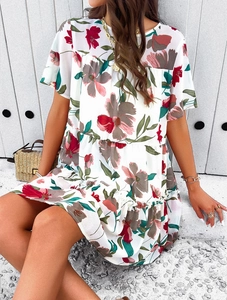 Dettaglio di un abito estivo in chiffon bianco con stampa floreale e orlo a balze su modella
