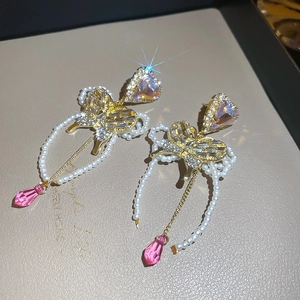 Macro view of crystal heart earrings with sparkling gold butterfly and pearl fringe