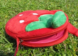 Detailed side view showing the plush strawberry bag texture and metal zipper closure