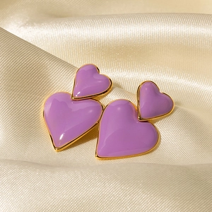 Dettaglio di orecchini a cuore viola con bordo dorato su seta color champagne