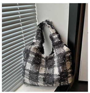 Close-up of the black and white checkered fabric texture and frayed tassel edges on this tote bag
