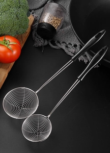 Close-up of small stainless steel spider strainers with black handles on a kitchen counter