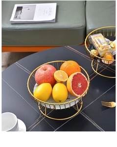 Détail d'un panier à fruits en métal doré avec socle en marbre blanc style nordique
