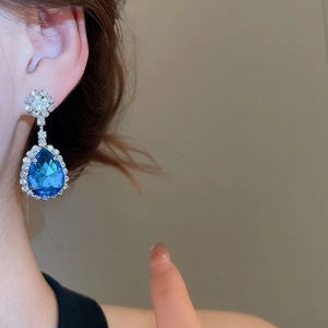 Detailed view of elegant pear-shaped blue gemstone earrings with diamond flower studs
