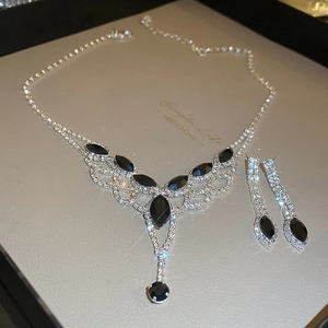 Elegant silver jewelry set with black navette stones and tassels on display card