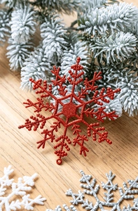 Dettaglio di fiocchi di neve rossi glitterati in plastica per decoro natalizio