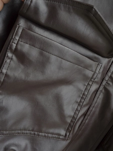 Macro detail of high-quality dark brown faux leather texture and stitching on jacket pocket