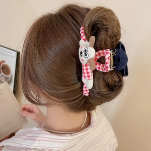 Pince à cheveux à carreaux rouges avec chien en peluche sur la coiffure du modèle