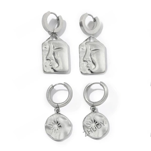 Detailed view of silver stainless steel earrings featuring abstract face and sun patterns