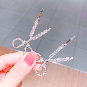 Detail of creative scissor-shaped hair clips with sparkling rhinestones in a pair
