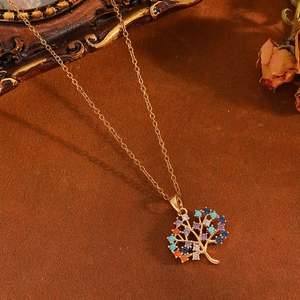 Golden Tree of Life necklace featuring colorful rhinestones on a textured brown backdrop