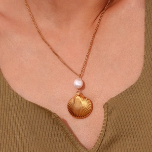 Detail of 18K gold-plated shell pendant and freshwater pearl necklace on model neck