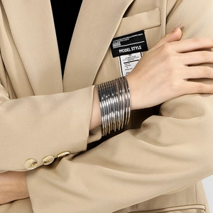 Polished silver stacked multilayer stainless steel bangles worn on a model's wrist