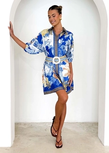 Dettaglio di un abito a camicia blu stampato con motivi barocchi e cintura beige