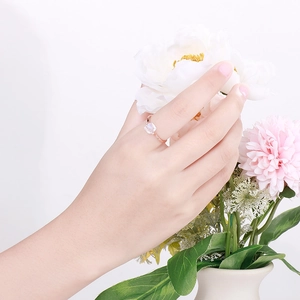 Detail of rose gold spinning ring featuring a rectangular clear zircon on model's finger