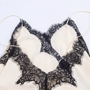 Détail d'un caraco en satin crème avec dentelle noire délicate et fines bretelles