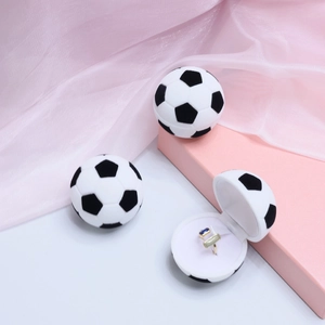 Macro view of a soccer-shaped ring box featuring white and black velvet finish details