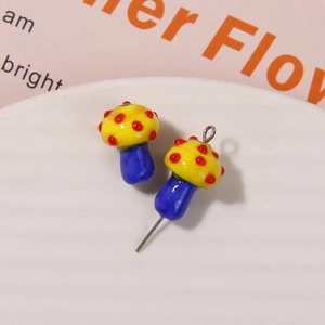 Detail of mushroom glass beads with yellow caps, red dots, and blue stems for DIY jewelry