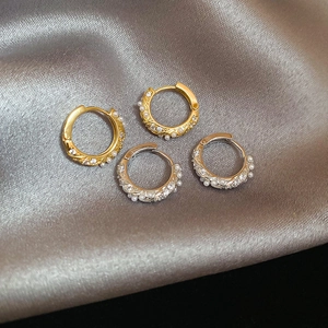 Detail of gold and silver hoop earrings with pearls and zircons on silk fabric