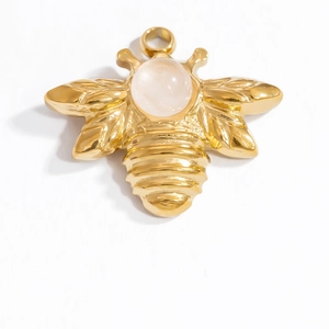 Detailed view of a gold bee pendant featuring a polished finish and a pink center gemstone