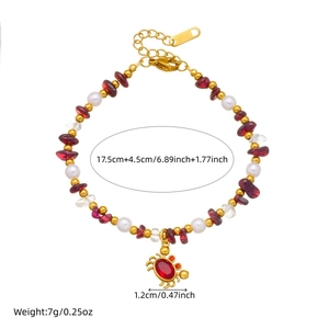 Bracelet vintage avec perles de grenat et de nacre avec un pendentif crabe doré sur fond blanc