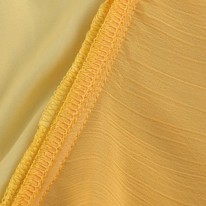 Gros plan sur la texture du tissu jaune montrant le tissage fin et les coutures de la robe