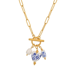 Detail of blue and white porcelain charms and pearl on a gold stainless steel necklace