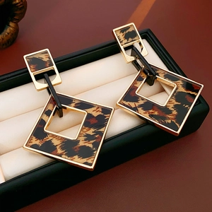 Macro detail of geometric leopard print earrings with gold metal frame on display case