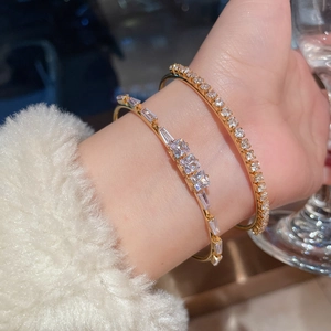 Close-up of 18K gold plated tennis bracelet and geometric zircon open bangle on wrist