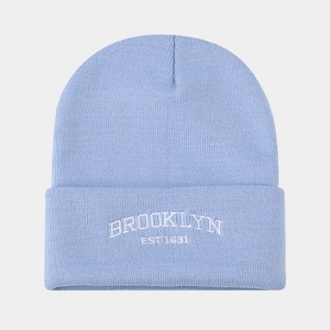 Detail of light blue knit beanie with Brooklyn Est 1631 white embroidery texture