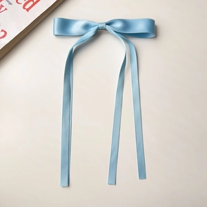Close-up of light blue ribbon bow hair clip with long streamers on a white background