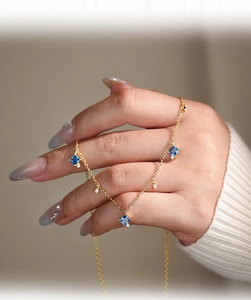 Close-up of S925 silver gold-plated necklace featuring square blue zircons on model