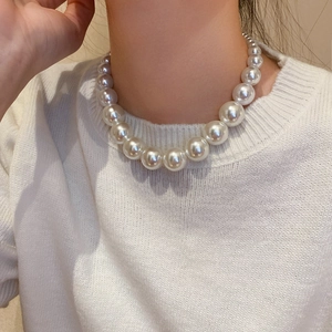 Detail of elegant white gradient pearl necklace shown on a white knitted sweater