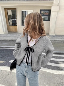 Light grey oversized knit cardigan with black bow ties and contrast trim detailing