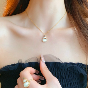 Detail of gold plated gourd earrings with white opal and zircons worn by a model