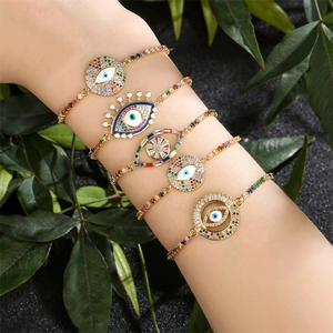 Macro shot of 5 layered gold evil eye bracelets with colorful zircon and Fatima hands