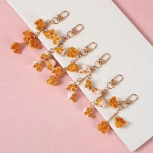 Realistic PVC popcorn keychains with golden lobster clasps on a pink background