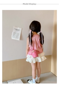 Pink child bucket bag with cherry print worn by a young model in a soft minimalist room